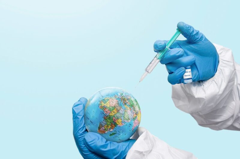 Hands in latex gloves injecting a globe with a syringe, symbolizing global vaccination efforts.