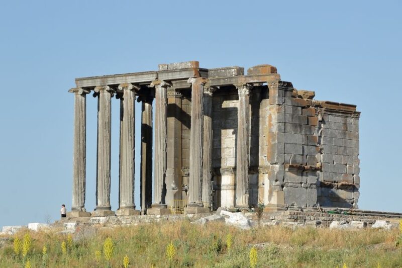 Ancient temple ruins with columns under a clear blue sky, showcasing historical architecture.